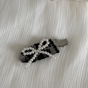 Detail view of lace bow hair clip featuring elegant white pearls and a silver metal alligator base