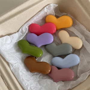 Makroaufnahme von 9 bunten glänzenden Herz-Haarspangen in einer Geschenkbox verpackt