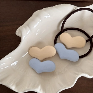 Nahaufnahme von herzförmigen Harz-Anhängern in Creme und Blau auf elastischen Haargummis