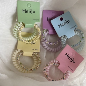 Close-up of pastel spiral hair ties with floral patterns and solid colors on cards