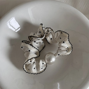 Detailansicht von Polka-Dot-Haargummi mit Spitzenrand und weißer Perlenverzierung