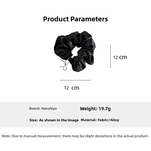 Détail d'un chouchou en tissu plissé noir avec breloque papillon et diamètre de 12cm