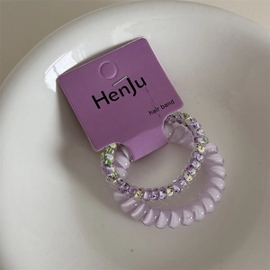 Macro view of purple floral and solid telephone cord hair ties on branded card
