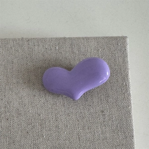 Detail einer minimalistischen lila herzförmigen Haarspange mit glänzender Glasur