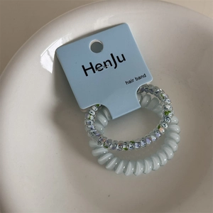 Floral and solid spiral hair ties set in a ceramic bowl with product packaging