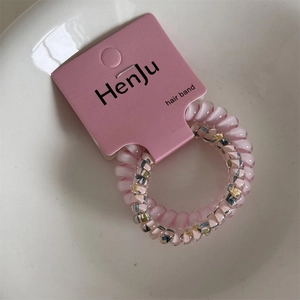 Detail of pink spiral phone cord hair tie with yellow floral pattern on card