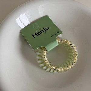 Detail of light green and floral spiral hair ties displayed in a white ceramic bowl