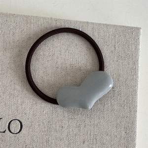 Nahaufnahme von minimalistischem Haargummi mit grauem Herz auf braunem Gummiband