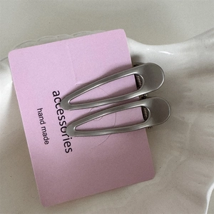 Gros plan de barrettes minimalistes en métal argenté sur carte rose avec texte fait main
