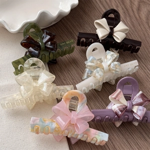 Elegant French acetate bow hair claw clips in various colors displayed on a wood surface