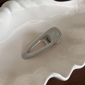 Detailed close-up of a silver smile hair clip on a white wave plate with macro focus