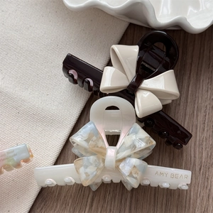 Macro shot of French acetate bow hair clips with marble pattern and brand lettering