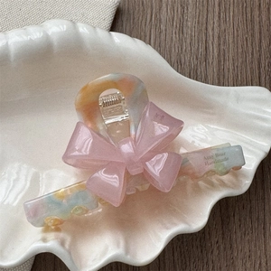 Detail of French acetate hair claw with pink bow design and marble texture finish