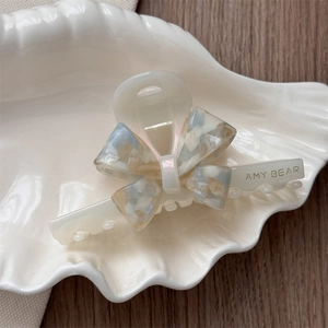 Detailed macro view of the acetate marble bow hair claw clip on a decorative shell dish