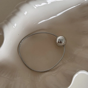 Close-up of a silver elastic hair tie with a shiny mirror metal ball on a shell-shaped plate