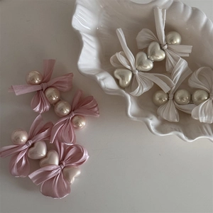 Elegante rosa und cremefarbene Haarklammern mit Schleifen und Perlen auf einer Schale