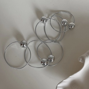 Set of shiny silver elastic hair bands with metallic beads on a minimalist background