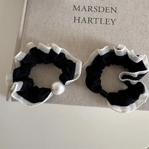 Close-up of black and white ruffled hair scrunchies with elegant faux pearl detail