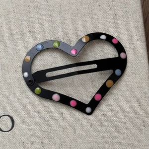 Détail de barrettes à cheveux en forme de cœur noir mat avec des pois colorés