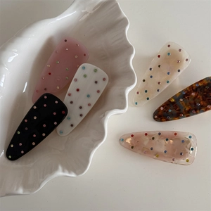 Lot de six barrettes à cheveux en acétate avec strass colorés sur un plateau en coquillage