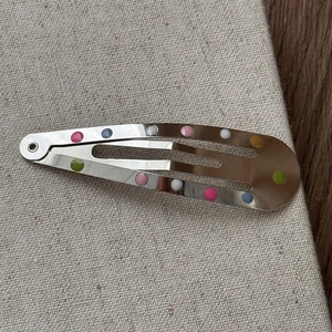 Gros plan détaillé de barrettes en métal à pois colorés sur un tissu texturé