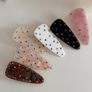 Détail de barrettes triangulaires avec strass colorés aux motifs marbre et écaille