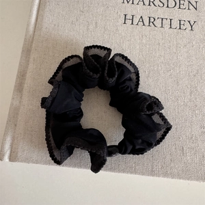 Detailed macro view of a vintage black lace scrunchie on an elegant grey book