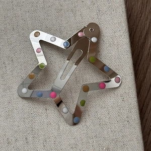 Détail de la pince à cheveux en forme d'étoile avec pois colorés sur une surface en toile