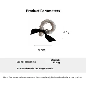 Detail view of pearl hair scrunchie with a black fabric bow and heart rhinestone charm