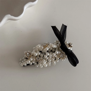 Detail of vintage pearl hair clip with black ribbon bow and sparkling rhinestone accents