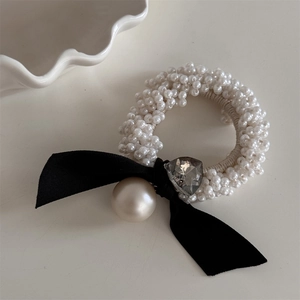 Detail of pearl hair tie with black velvet bow, heart crystal, and large pearl pendant