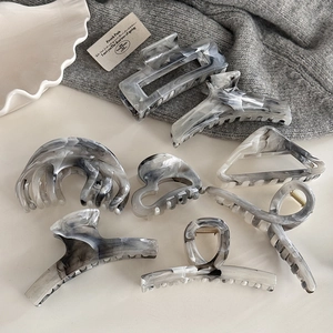 Macro detail of various ink wash pattern hair claws in geometric acetate styles