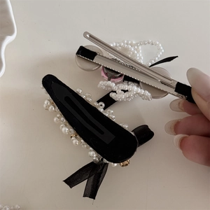 Detailed view of pearl bow hair clips with black ribbon and pink accents