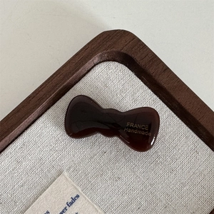 Detail of a dark brown acetate bow hair clip with gold France Handmade lettering