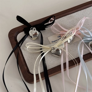 Detalle de pinzas para el cabello con lazos de cinta y colgantes de corazón en bandeja
