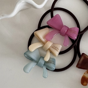 Detailed macro view of acetal resin bow hair ties with handmade logo text and elastic band