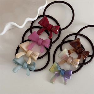 Close-up of assorted handmade acetate bow hair ties in vibrant colors on a white surface