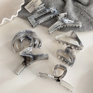 Macro detail of various marble pattern hair claws set on a minimalist aesthetic background