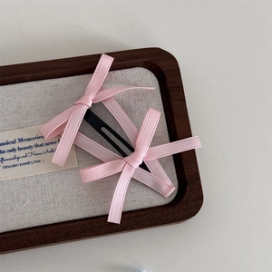 Primo piano di un fermaglio per capelli a fiocco rosa su un vassoio per gioielli in lino