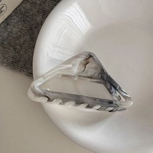 Detail view of gray marble geometric hair claw clip resting on a white ceramic tray
