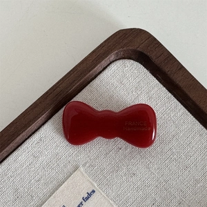 Macro detail of high-gloss red acetate bow hair clip with France Handmade lettering