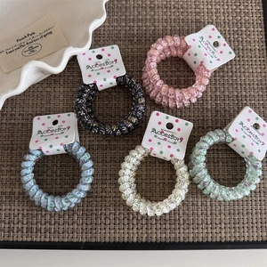 Set of five floral pattern spiral hair ties on a textured background with elegant packaging