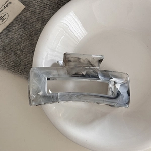 Macro shot of rectangular acetate hair claw clip with grey ink marble texture finish