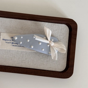 Dettaglio del fermaglio per capelli azzurro a pois con fiocco in seta beige