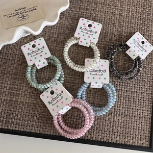 Colorful pastel telephone wire spiral hair ties on rustic woven background