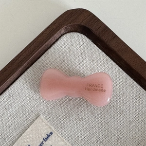 Detailed macro view of a pink acetate bow hair clip with silver France Handmade logo