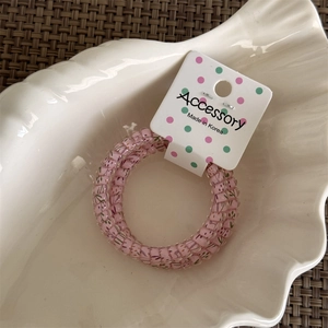 Close-up of pink floral telephone wire hair ring with polka dots on a white shell plate