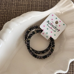 Close-up of two-piece beaded elastic hair ties with butterfly patterns on a white tray