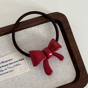 Detailed close-up of a high-elasticity red bow hair tie on a vintage display tray