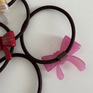 Detail of colorful resin bow hair ties with gold handmade lettering and elastic bands